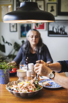 Cropped image of man serving salad at dining table