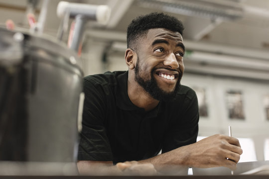 Smiling young male high school student looking away in workshop