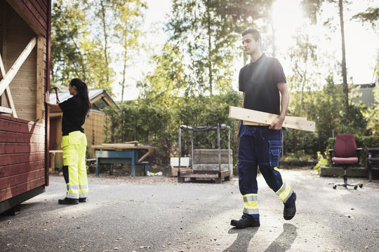 Man and woman building wooden cabin