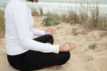 Woman meditating on the beach sitting with yoga pose