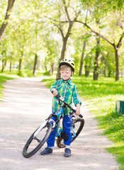child with a bicycle in a summer park