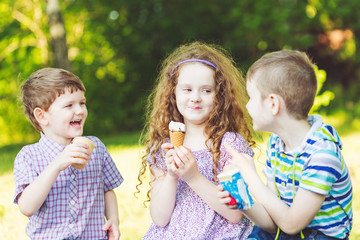 Children enjoy eating ice cream in summer park.