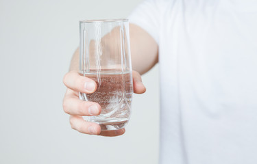 Young man holding a glass with water