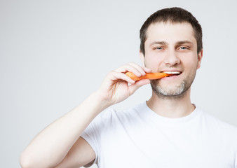Happy young man eating a carrot