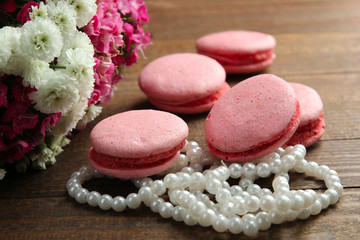 macaroons with beads on wooden background near the pile of flowers