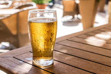 Glass of light beer on the wooden table.
