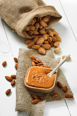 Homemade almond butter in a wooden bowl and a bag of jute.