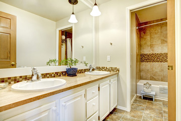 Golden bathroom interior with wood white painted cabinets.