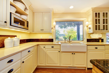 Cream color kitchen with large white sink and classic design.