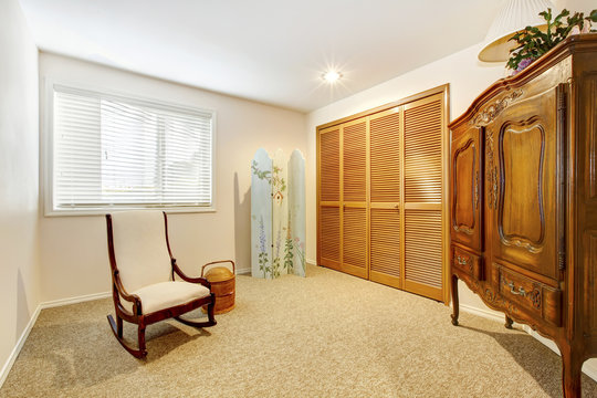 Guest room with armore , closet doors and chair.