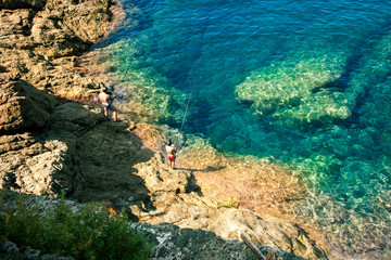 Father and son fishing on isolated ocean coastline