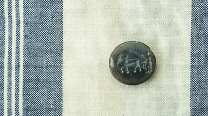 Ancient seal crafted the image of human plowing  by animals on fabric background