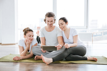 Fototapeta na wymiar Man and two women using tablet in yoga studio together