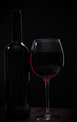Elegant red wine glass and a wine bottle