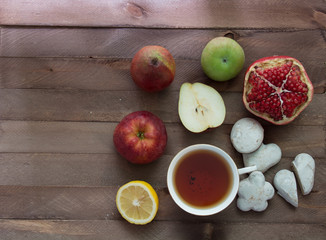 Garnets, apples, lemon, cookies and a cup of tea on a wooden table