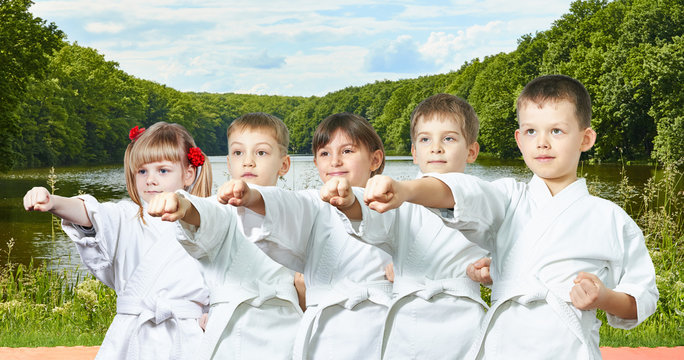Young children are hitting a punch arm on the background of nature and water