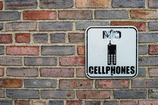 No Cell Phones Warning Sign On Brick Wall Background