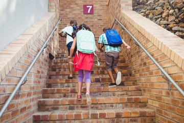 Three school kids climbing brick stairs