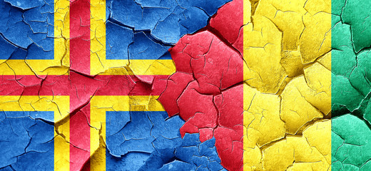 aland islands with Guinea flag on a grunge cracked wall