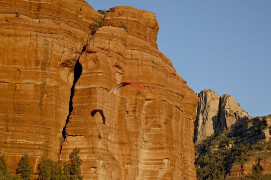 A paraglider flies past a red rock formation, Coconino National Forest, Arizona