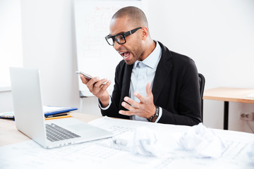 Angry businessman in stress talking on mobile phone