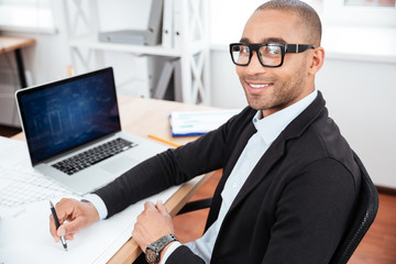 Young businessman sitting in the office and looking at camera