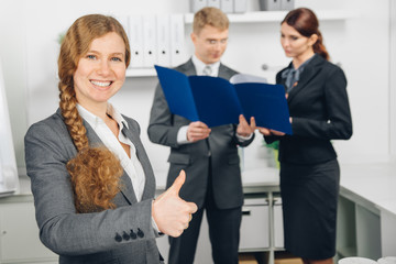 business woman working in office shows thumb up