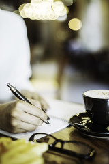 portrait image of a woman writing her notebook in a cafe
