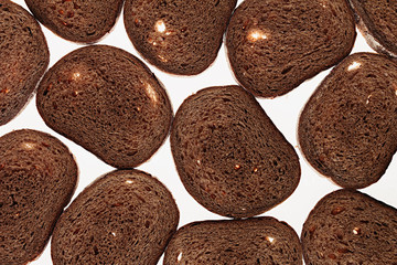 Slices of black rye bread on a white background. Food background. Pattern.