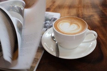 Coffee Latte art  with open book on the wood table.