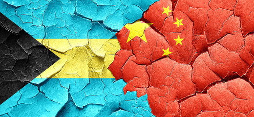 Bahamas flag with China flag on a grunge cracked wall