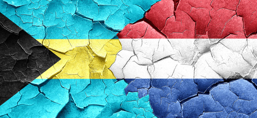 Bahamas flag with Netherlands flag on a grunge cracked wall