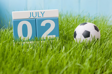 July 2nd. Image of july 2 wooden color calendar on green lawn grass background. Summer day