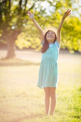 Smiling girl standing with arms outstretched in park