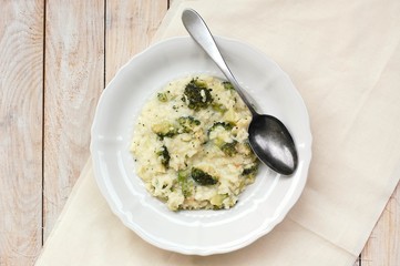 Creamy risotto with broccoli on the cloth and wooden background
