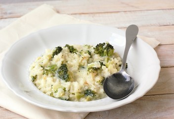 Creamy risotto with broccoli on the cloth and wooden background