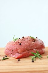 Raw pork meat tenderloin with black pepper and rosemary on wood prepared to cook