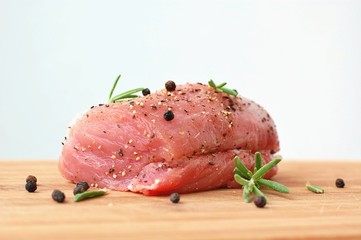 Raw pork meat tenderloin with black pepper and rosemary on wood prepared to cook