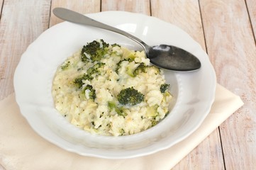 Creamy risotto with broccoli on the cloth and wooden background