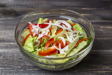 Fresh salad with herbs, paprika and onion in glass plate