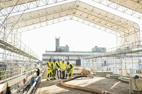 Workers at construction site looking at  blueprints