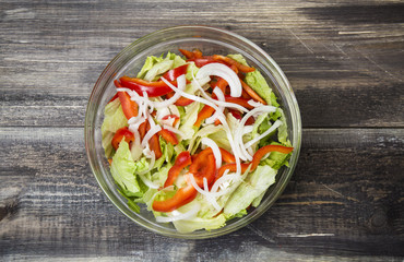 Fresh salad with herbs, paprika and onion in glass plate