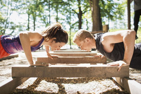 Young woman and man doing push ups in park
