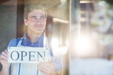 Smiling chef holding open sign