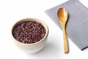 gruel (dark violet rice) in ceramic bow and wooden spoon isolated on white background