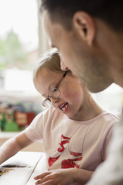 Girl with down syndrome studying by father at home