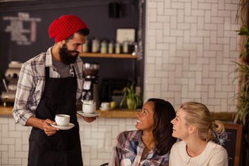 Waiter serving coffee and interacting with customers