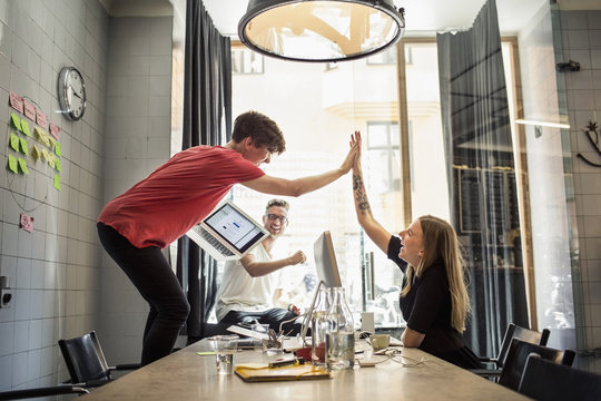Young people giving high five in creative office 