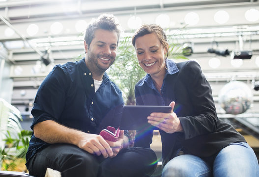 Smiling business people sharing digital tablet in cafe