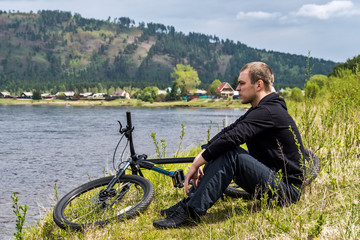 Obraz premium cyclist sits on the bank of river Irkut